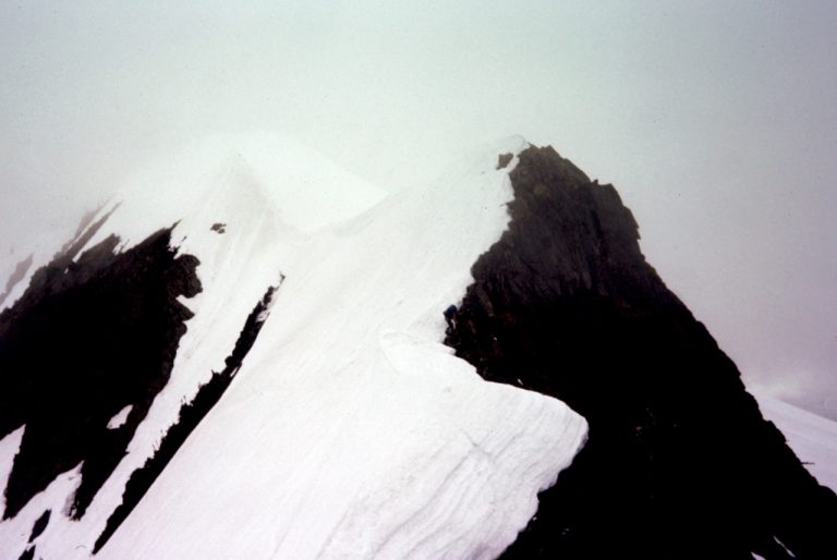 The undulating summit ridge of Rock Mountain is plastered by snow on one side and has dark rock on the other side