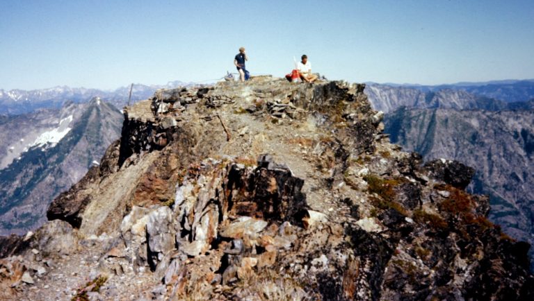 Two mountain climbers sit on the summit of Mt David in the Glacier Peak Wilderness