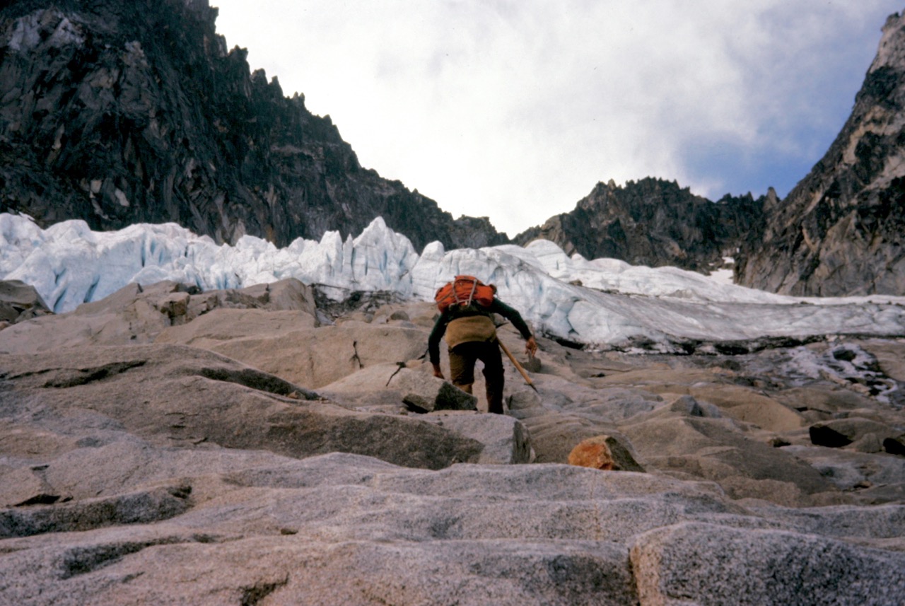 A mountain climber scrambling steep rock slabs which lead to the Sherpa Glacier on Mt Stuart in the Icicle Mountains
