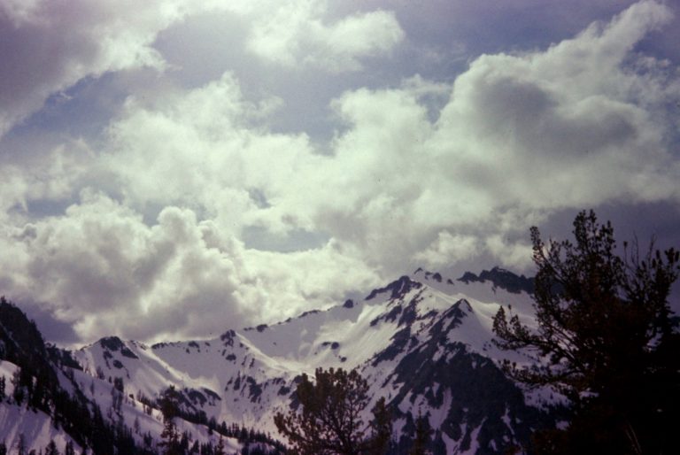 Puffy cumulus clouds build over the snowy summit of The Cradle in the Alpine Lakes Wilderness