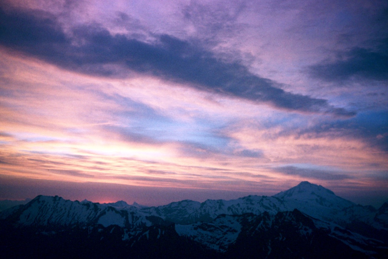 Sunset creates a pastel colored sky over the Cascade Range seen from Mt David in the Glacier Peak Wilderness