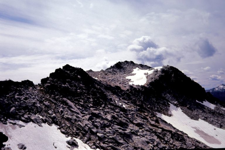 Grindstone Mountain summit with snow patches and scree as seen from ridge above Chatter Creek Pass