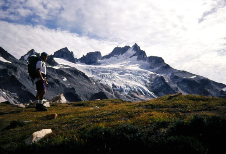 A mountain climber stands in front of Dome Peak in the North Cascades