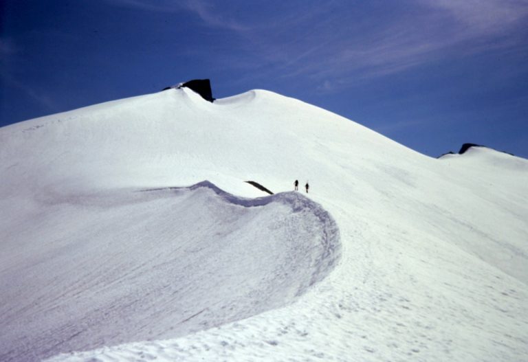 Two climbers ascend a snowy ridge crest on Ruth Mountain in the Nooksack Mountains