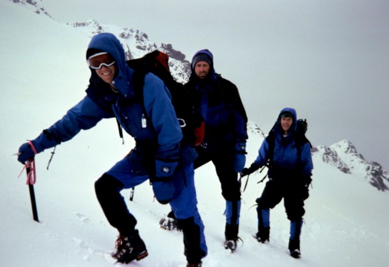Three mountain climbers ascend a snowy slope high on Cadet Peak