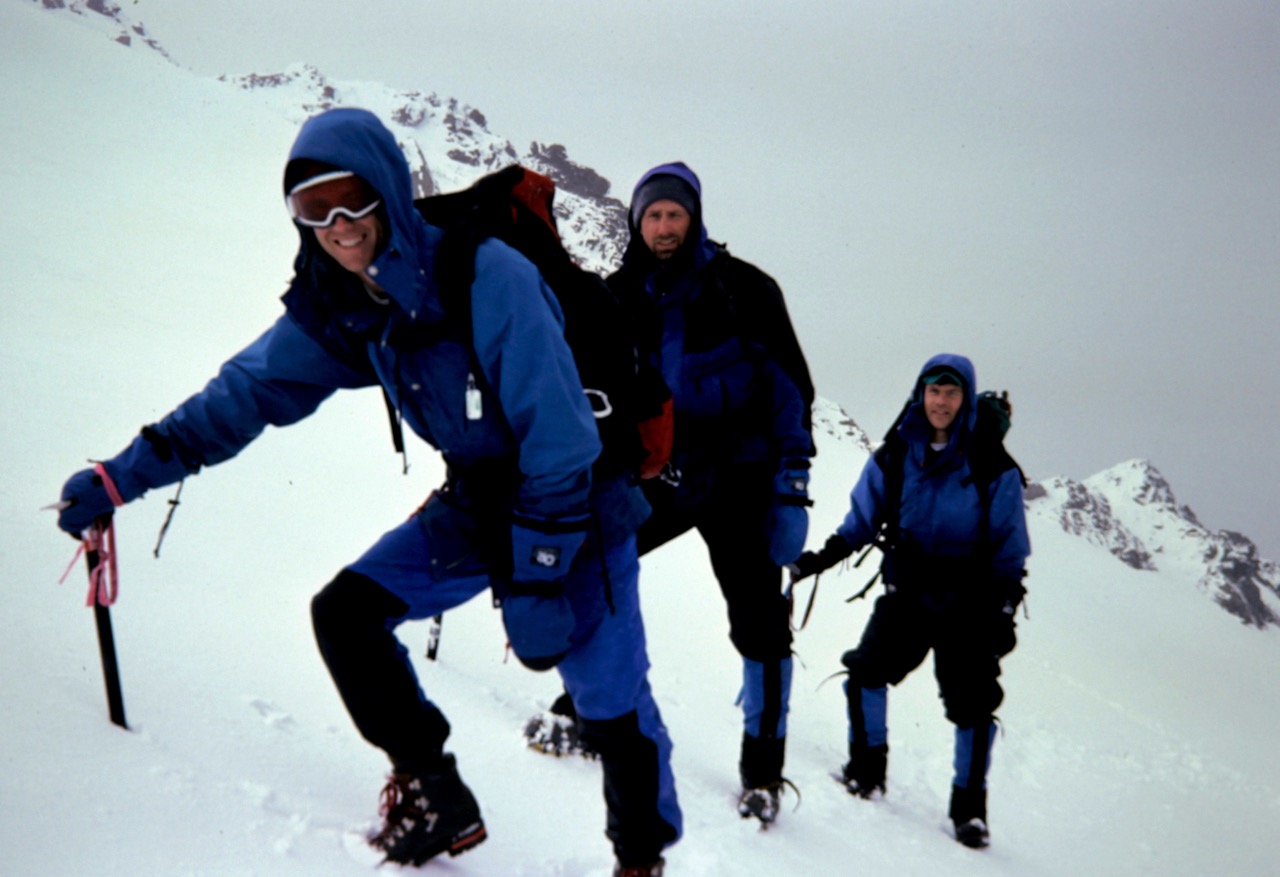 Three mountain climbers ascend a snowy slope high on Cadet Peak