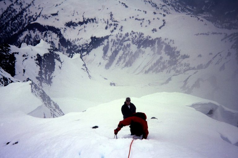 Two snow climbers ascending steep Summit Pyramid of Mt Shuksan above Sulphide Glacier