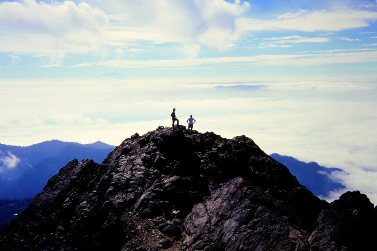 Two mountain climbers standing on the south summit of The Brothers Mountain in the Olympic Mountains