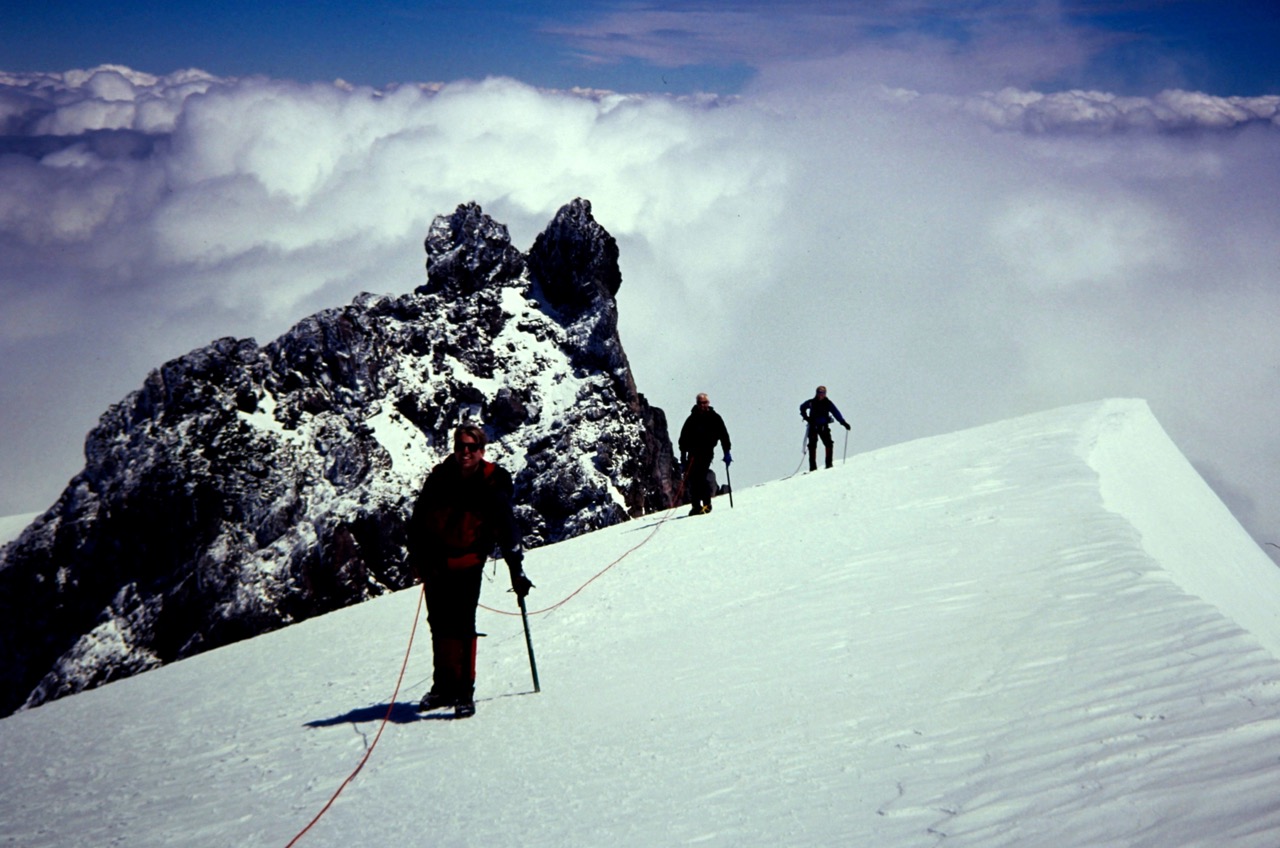 Mountain climbers on Glacier Peak stop above a distinctive rock formation called the Rabbit Ears
