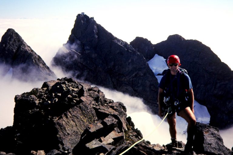 A climber stands atop North Finger while South Finger is visible in the background