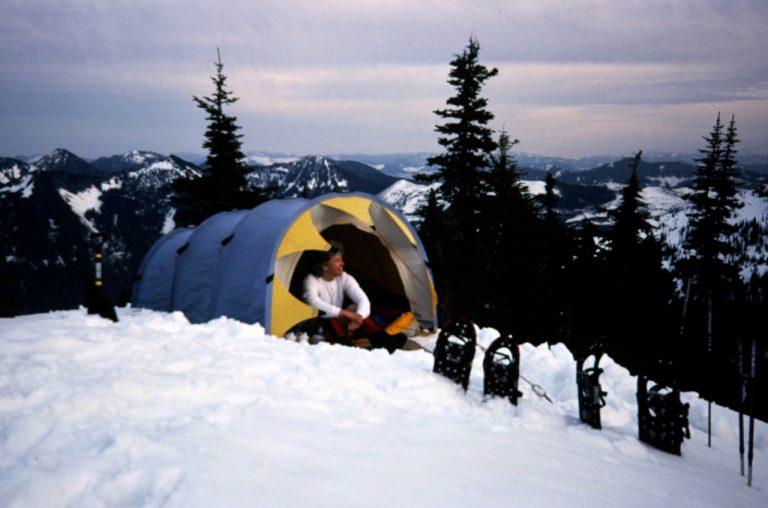 A snowshoer sits in a tent atop Pratt Mountain
