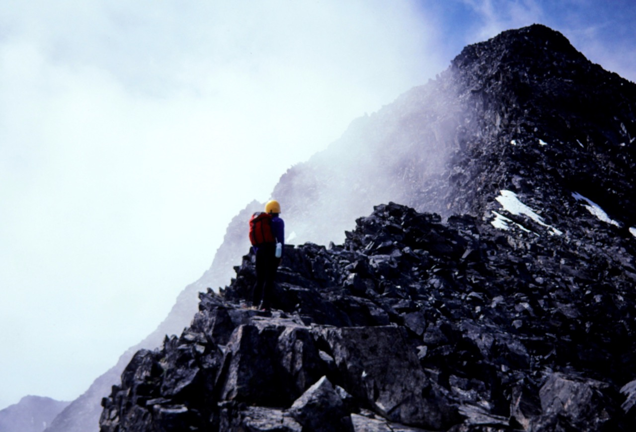 A climber stands on a steep rocky ridge on Copper Peak