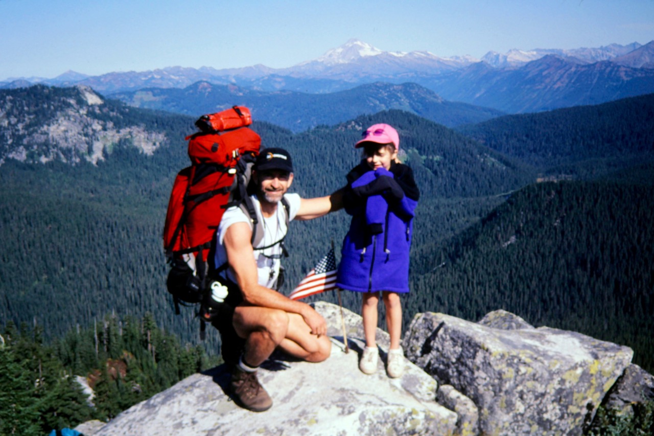 A man and young girl stand on the summit of Mt McCausland