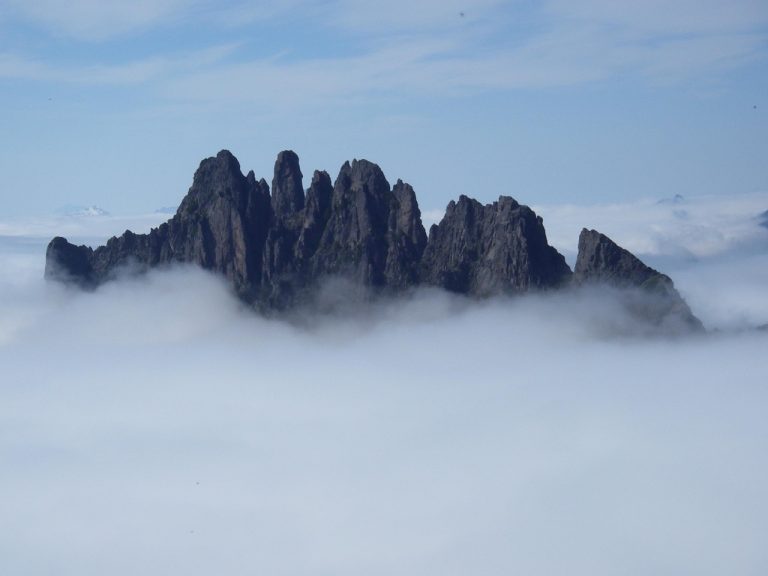 The craggy summit of Spire Mountain juts through a thick layer of fog