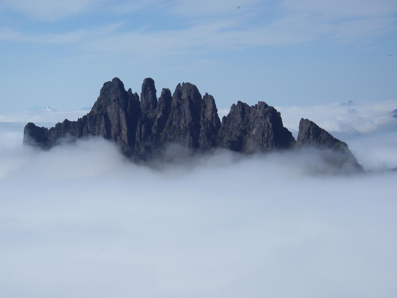 The craggy summit of Spire Mountain juts through a thick layer of fog