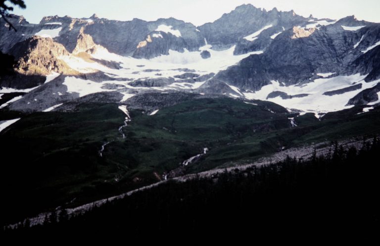The broad pyramid of Forbidden Peak rises above the green slopes of Boston Basin