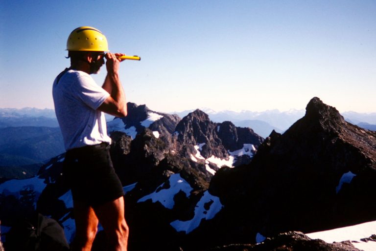 A mountain climber uses a hand-level instrument to survey the elevation of a Cadet Peak