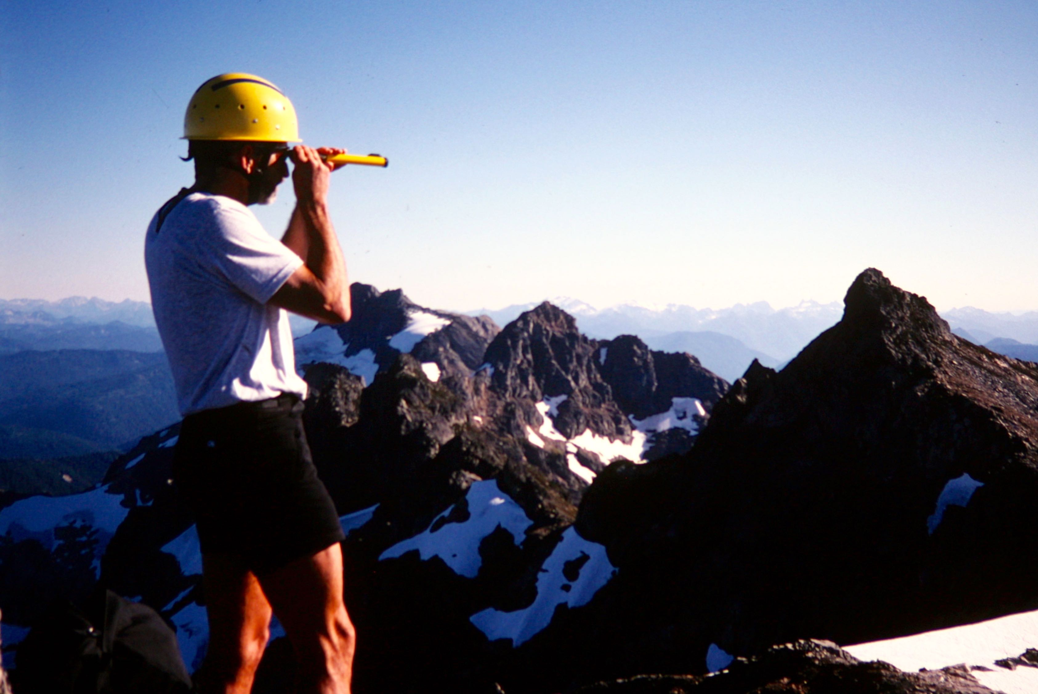 A mountain climber uses a hand-level instrument to survey the elevation of a Cadet Peak