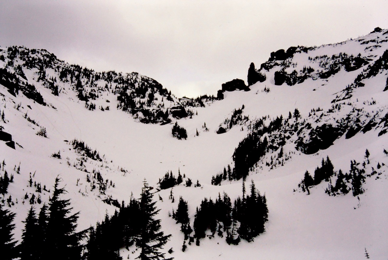 Snow slopes lead up to snowy and rocky Knapsack Pass