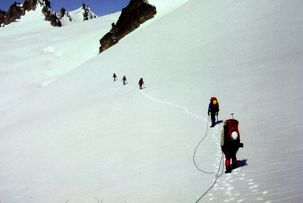 roped mountain climbers traverse vast snow field heading towards Dorado Needles on the Inspiration Traverse in the North Cascades 
