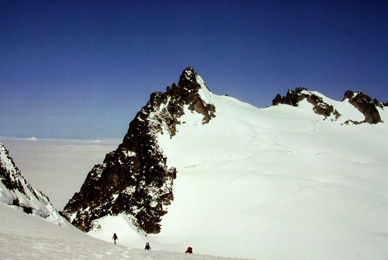 mountain climbers descending snow field with snow covered Dorado Needle in the North Cascades in the background