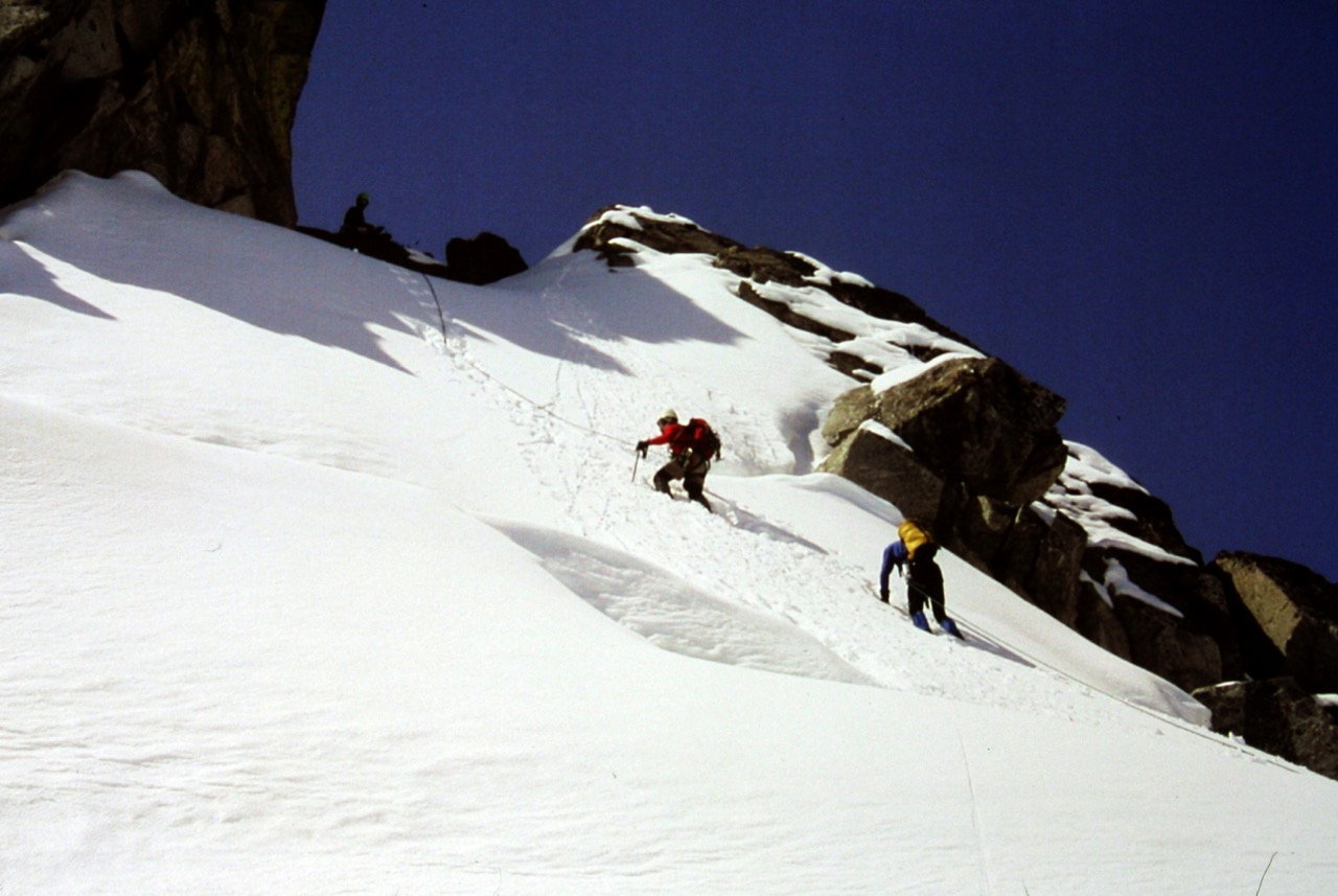 roped mountain climbers booting up steep snow field at the base on Dorado Needle on the Inspiration Traverse in the North Cascades