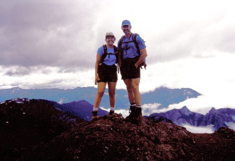 Two mountain climbers pose on the summit of Mt Angeles in the Olympic Mountains