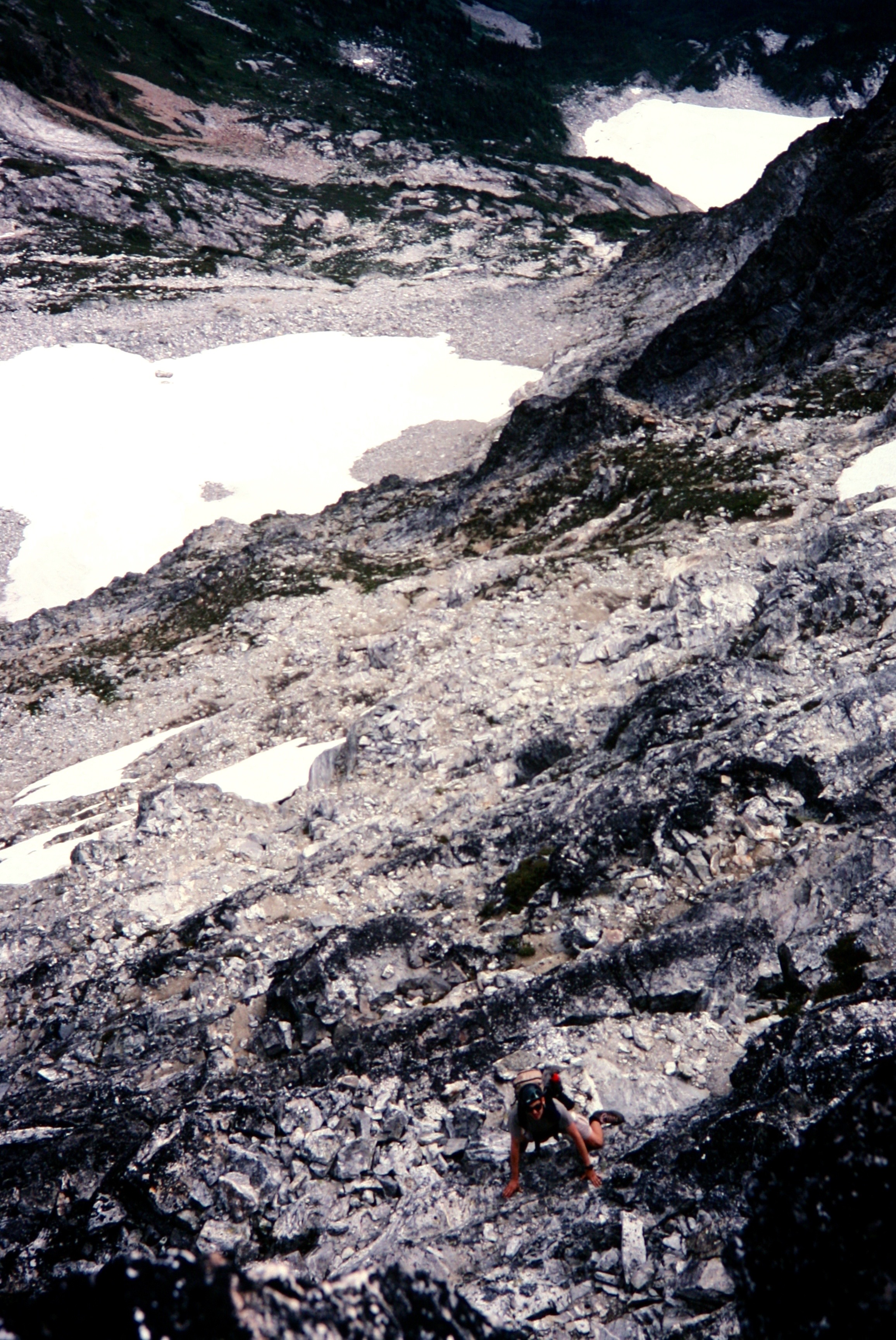 looking down on mountain climber scrambling up steep rocky face of Luna Peak in the Northern Pickets