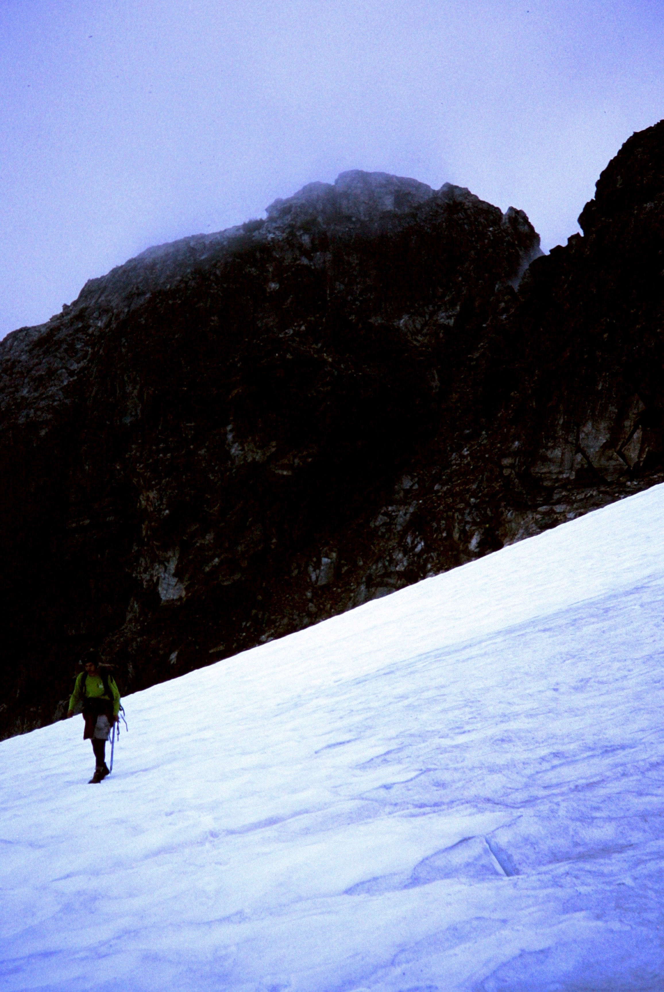 lone mountain climber traversing the snow with rocky monds leading to Luna Col in the Northern Picket Range