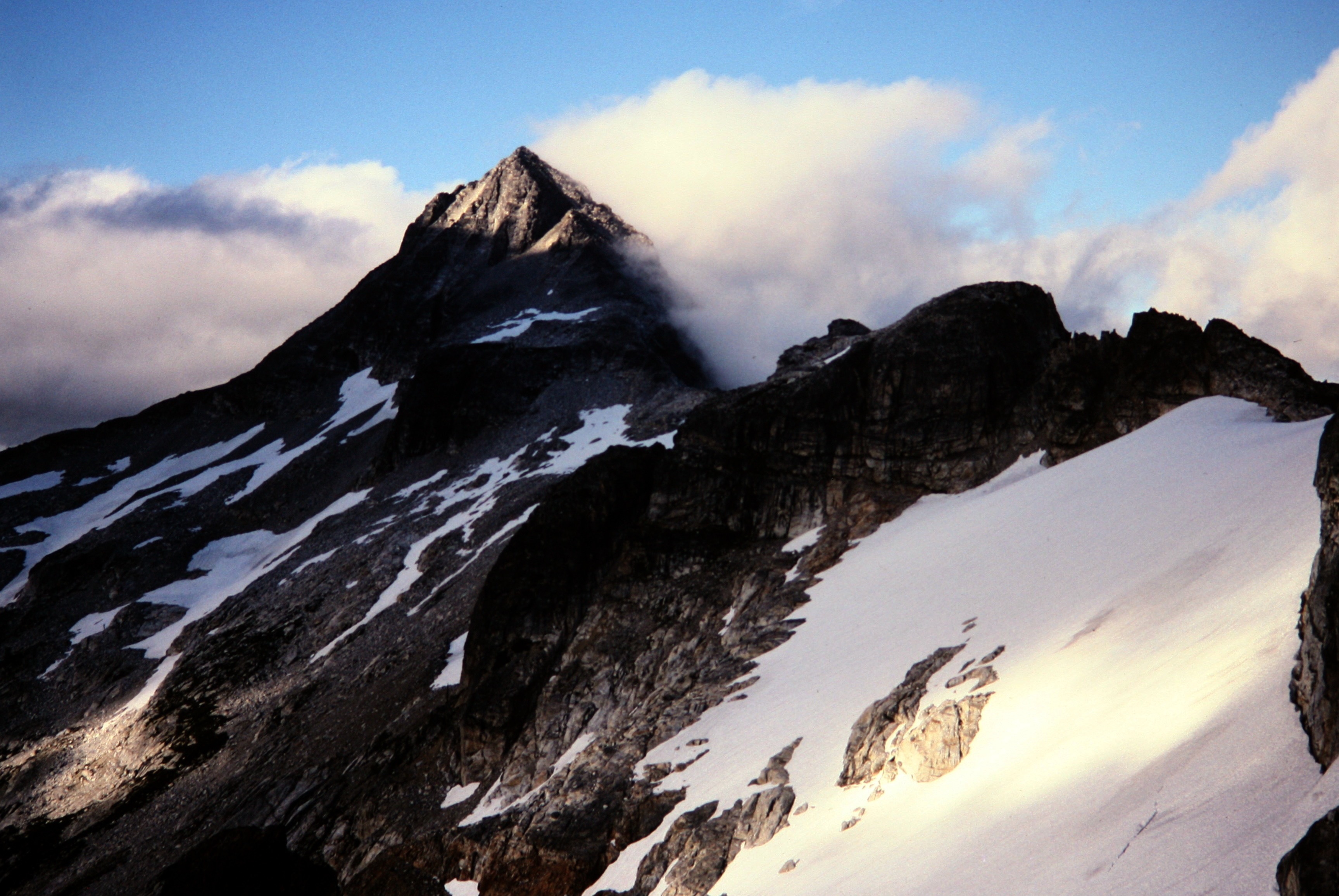 Evening Sun On Luna Peak with drifting clouds and linguring snow patches in the Northern Pickets