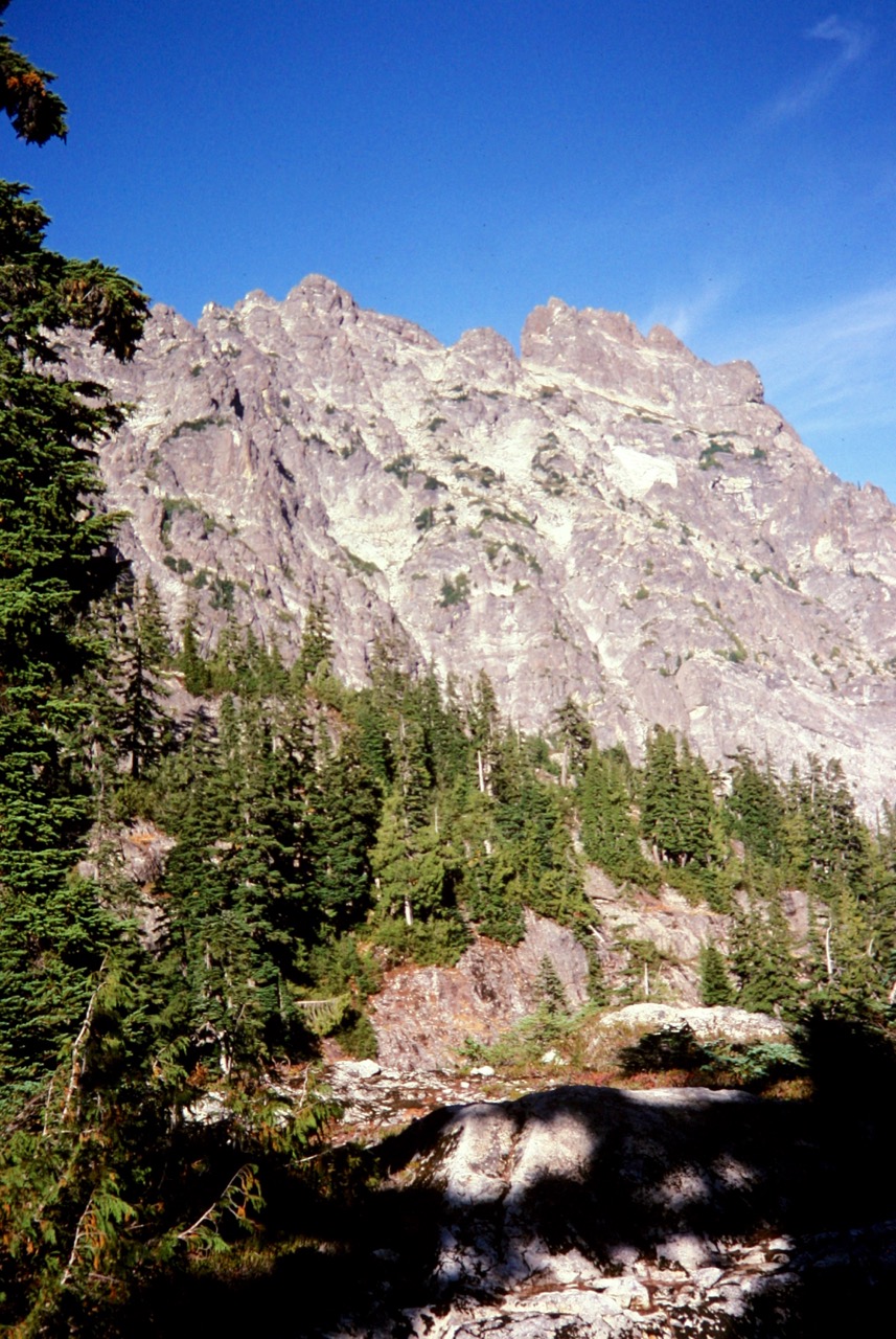 steep, rocky face of Bears Breast Mountain in the Alpine Lakes Wilderness with evergreen trees in the foreground as seen from Dutch Miller Gap