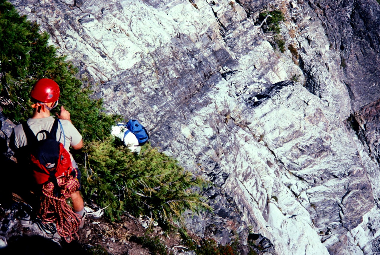 mountain climbers carefully descending alpine shrubs to reach the vertical, rock slabs of Bears Breast Mountain in the Alpine Lakes Wilderness