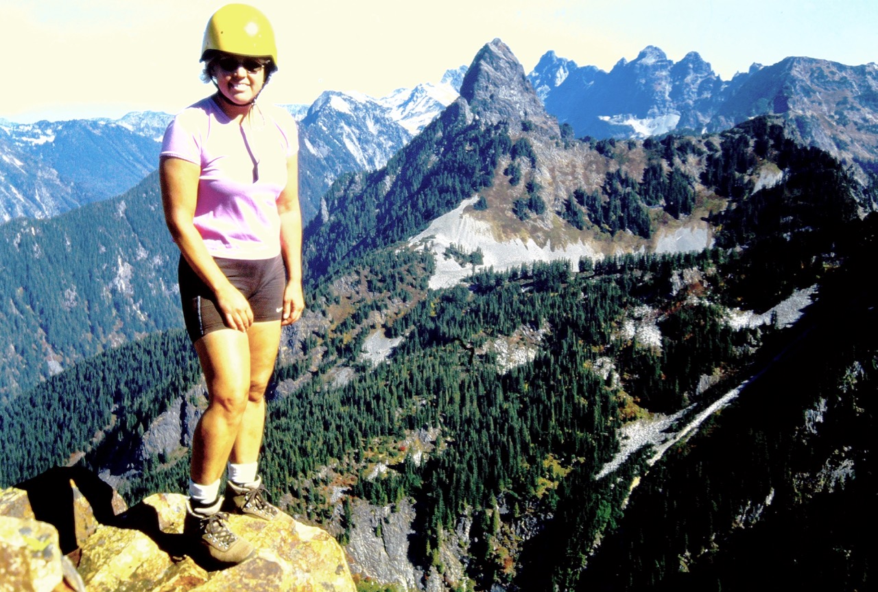 A female climber stands on Red Mountain with Mt Thomson in the background