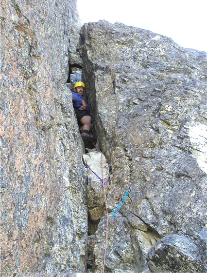 mountain climber in the crux rock chimney on the summit tower of Bears Breast Mountain in the Alpine Lakes Wilderness
