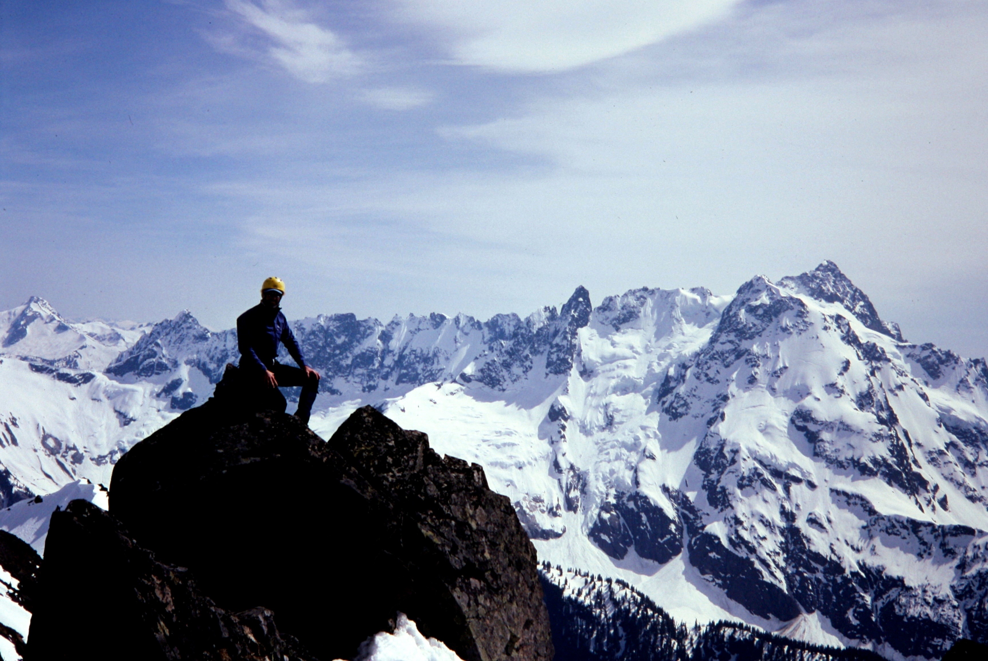 A mountain climber sits on Mt Sefrit amidst a sea of glaciated peaks