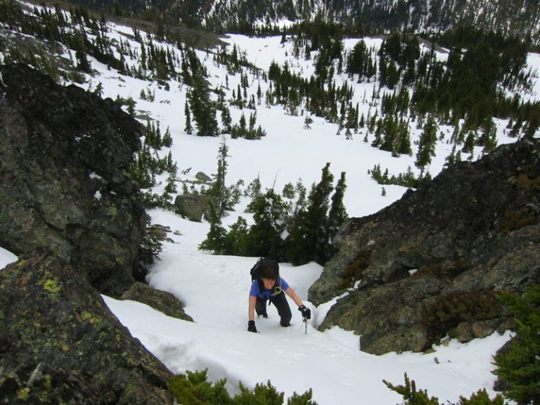A solo climber ascends a steep snow chute on High Esmerelda Peak