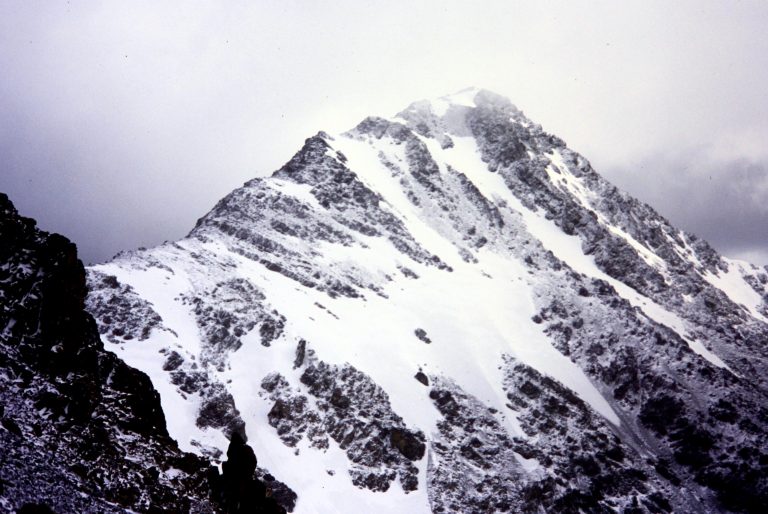 Looking along rocky ridge at snow-dusted summit of North Gardner Mountain