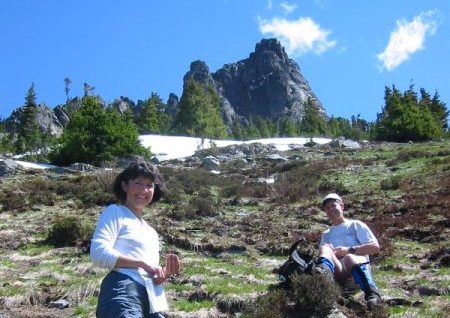 Two hikers pause below rocky Hibox Peak in the Snoqualmie Mountains
