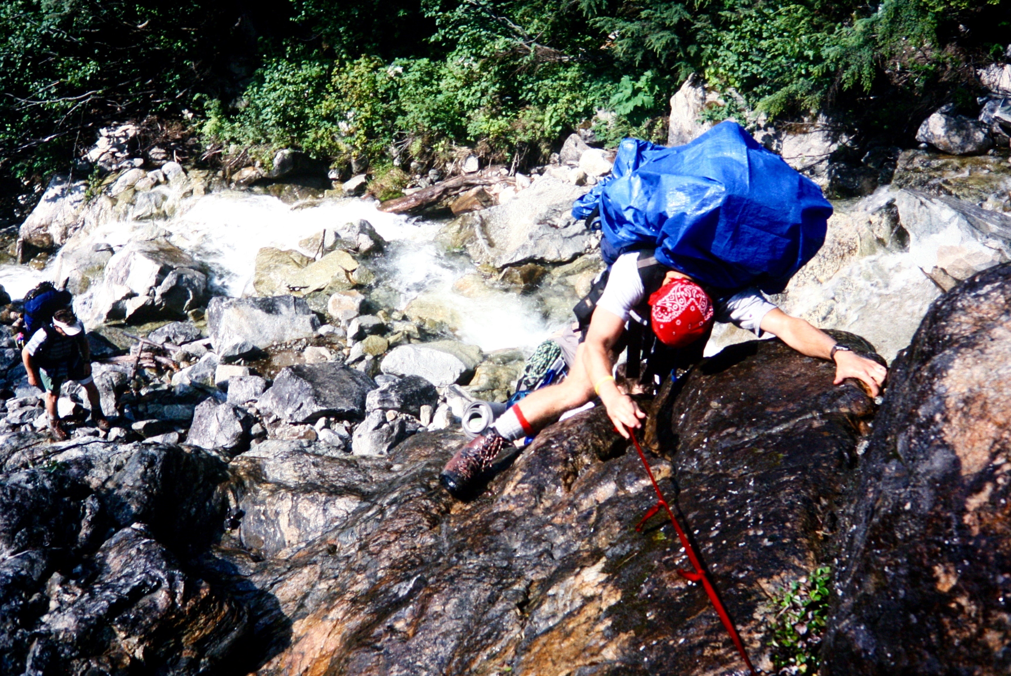 mountain climber scrambling wet boulders in Depot Creek Falls in the American Chilliwack Mountains