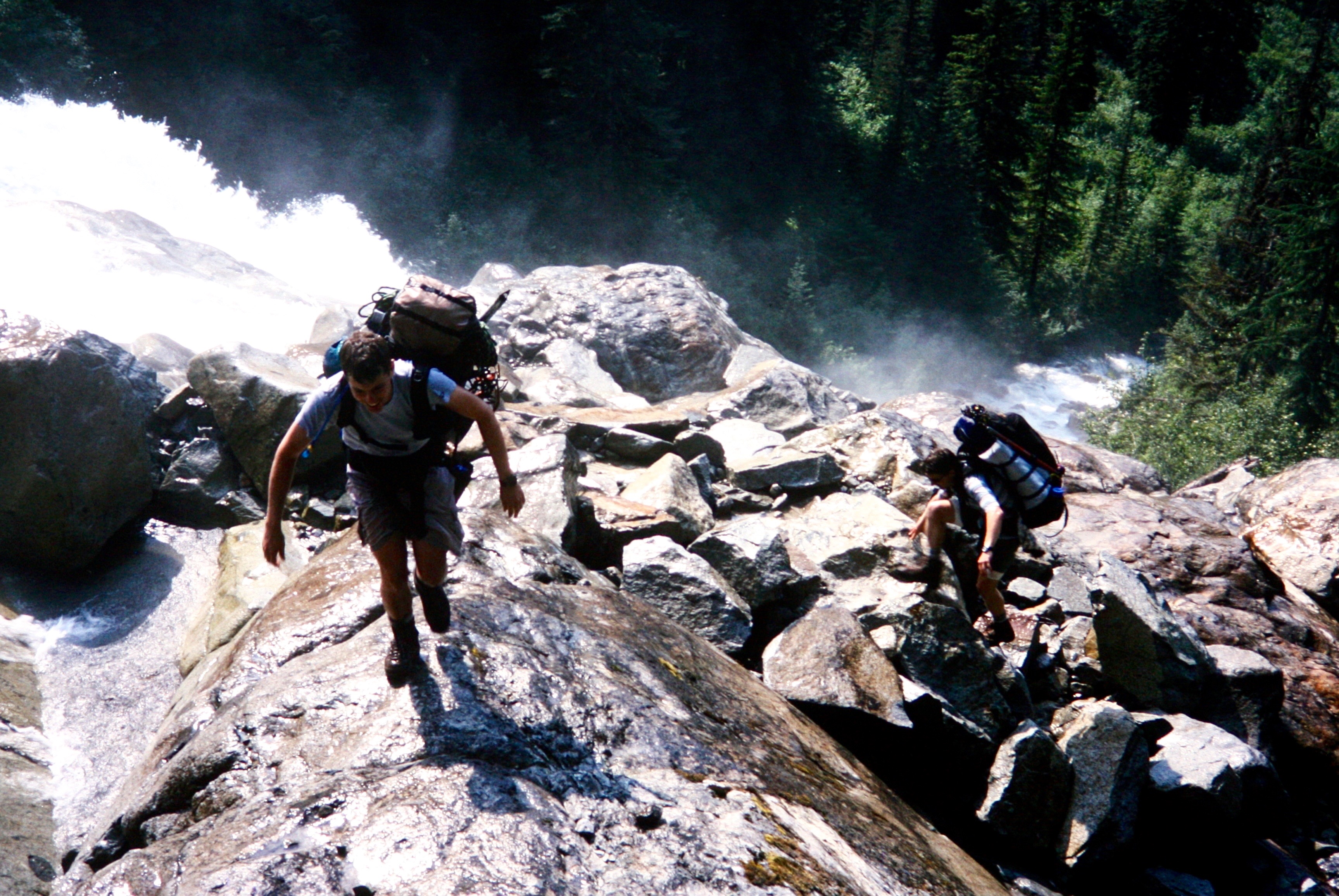 mountain climbers carefully hiking on wet boulders in Depot Creek Falls in the American Chilliwack Mountains