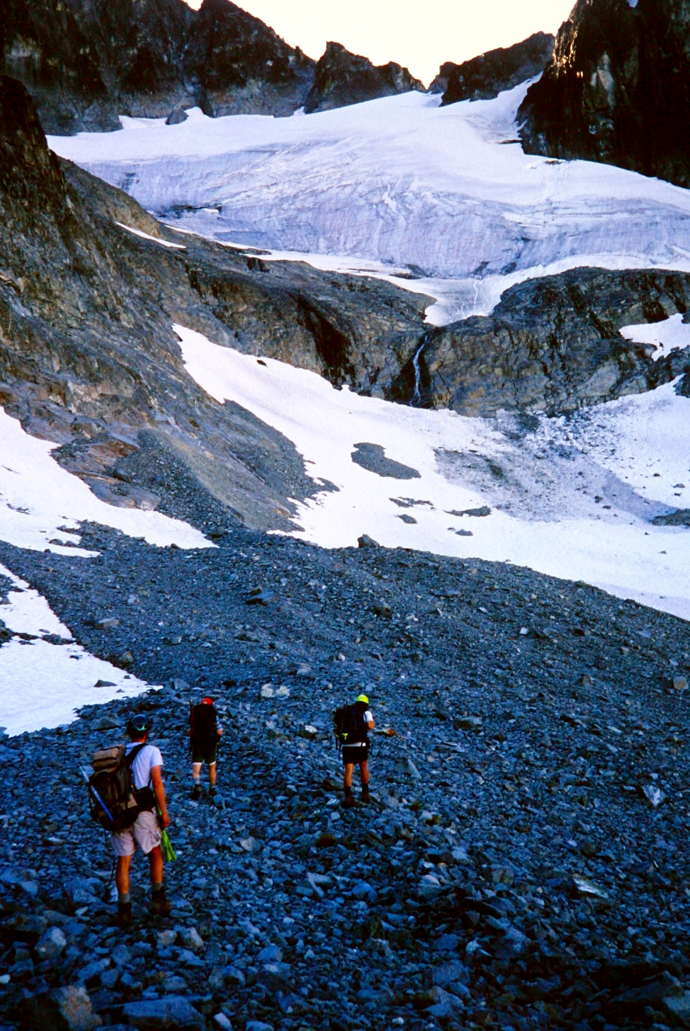 mountain climbers crossing scree field heading to snow slopes on Mt Spickard in the American Chilliwack Mountains
