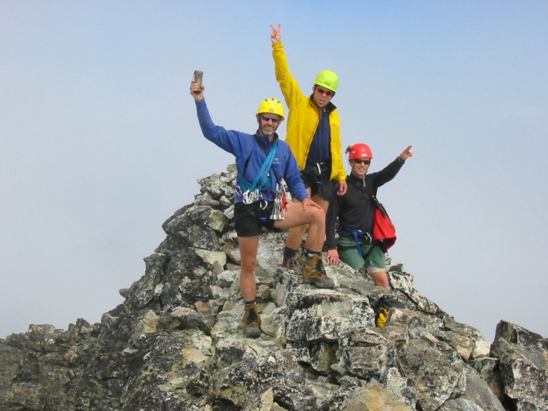 group of mountain climbers celebrating on the rocky summit horn of Mt Redoubt in the American Chilliwack Mountains