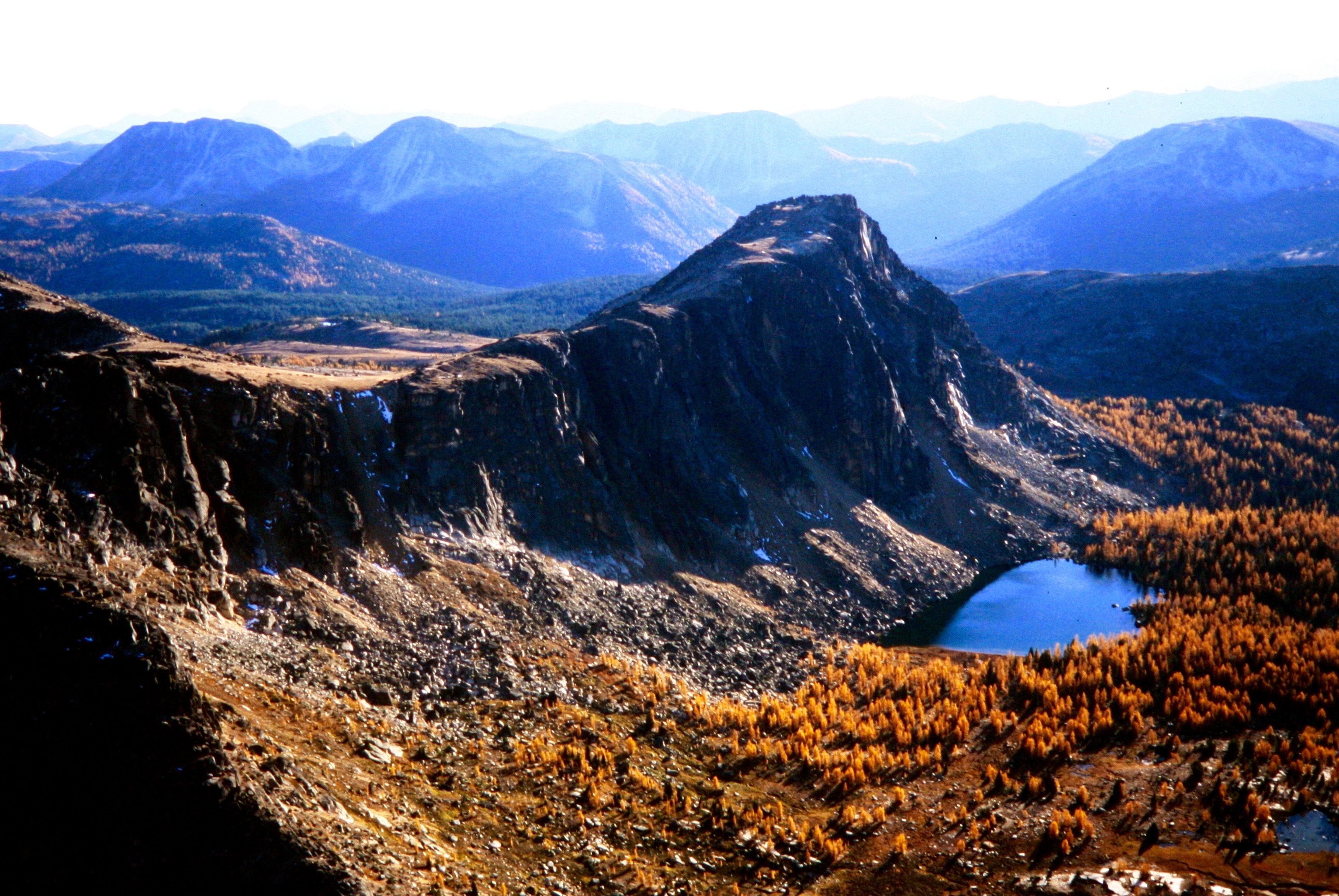 rocky ridges in the Similkameen Mountains with golden larch trees in the basin as seen from the summit of Cathedral Peak in the Similkameen Mountains in the Pasayten Wilderness