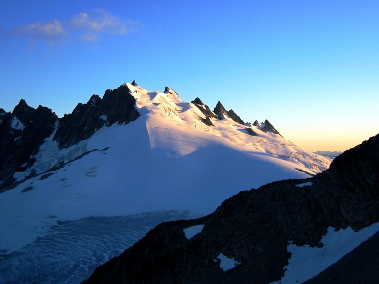 Soft sunlight hits the broad Challenger Glacier under the jagged crest of Mt Challenger