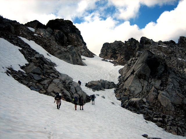 mountain climbers traversing snow fields heading to Thornton Ridge in the Lower Skagit Mountains with exposed boulders