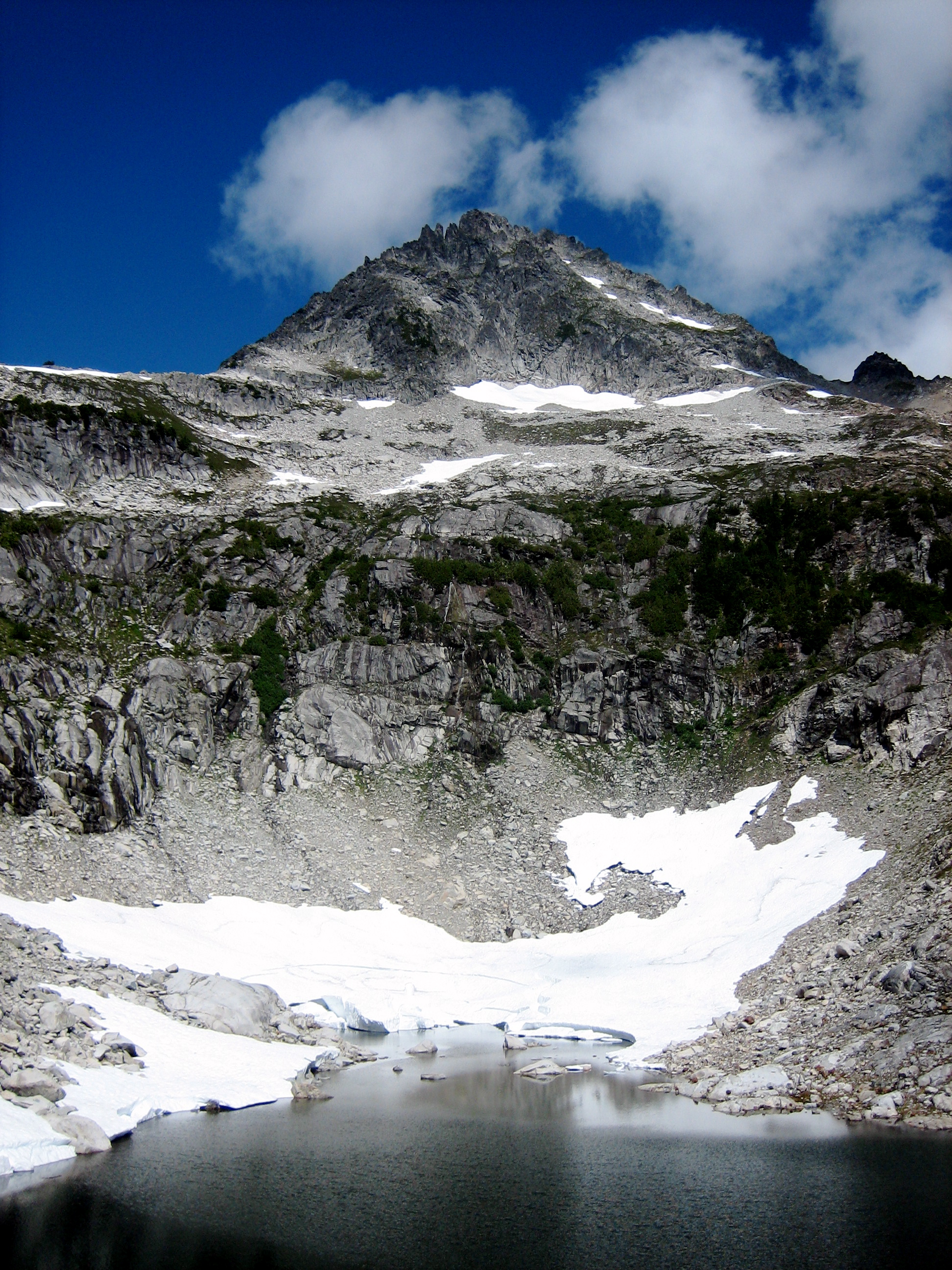 Mt Despair in the Lower Skagit Mountains with Upper Despair Lake in North Cascades National Park with steep rock cliffs and snow patches