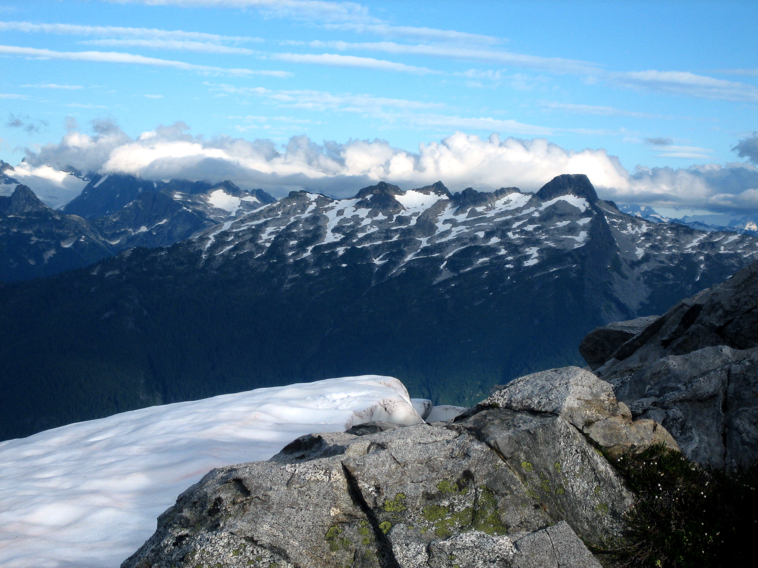 North Casccades National Park mountain range in the distance with snow fields and high clouds and Thornton Ridge in the Upper Skagit Mountains in the foreground