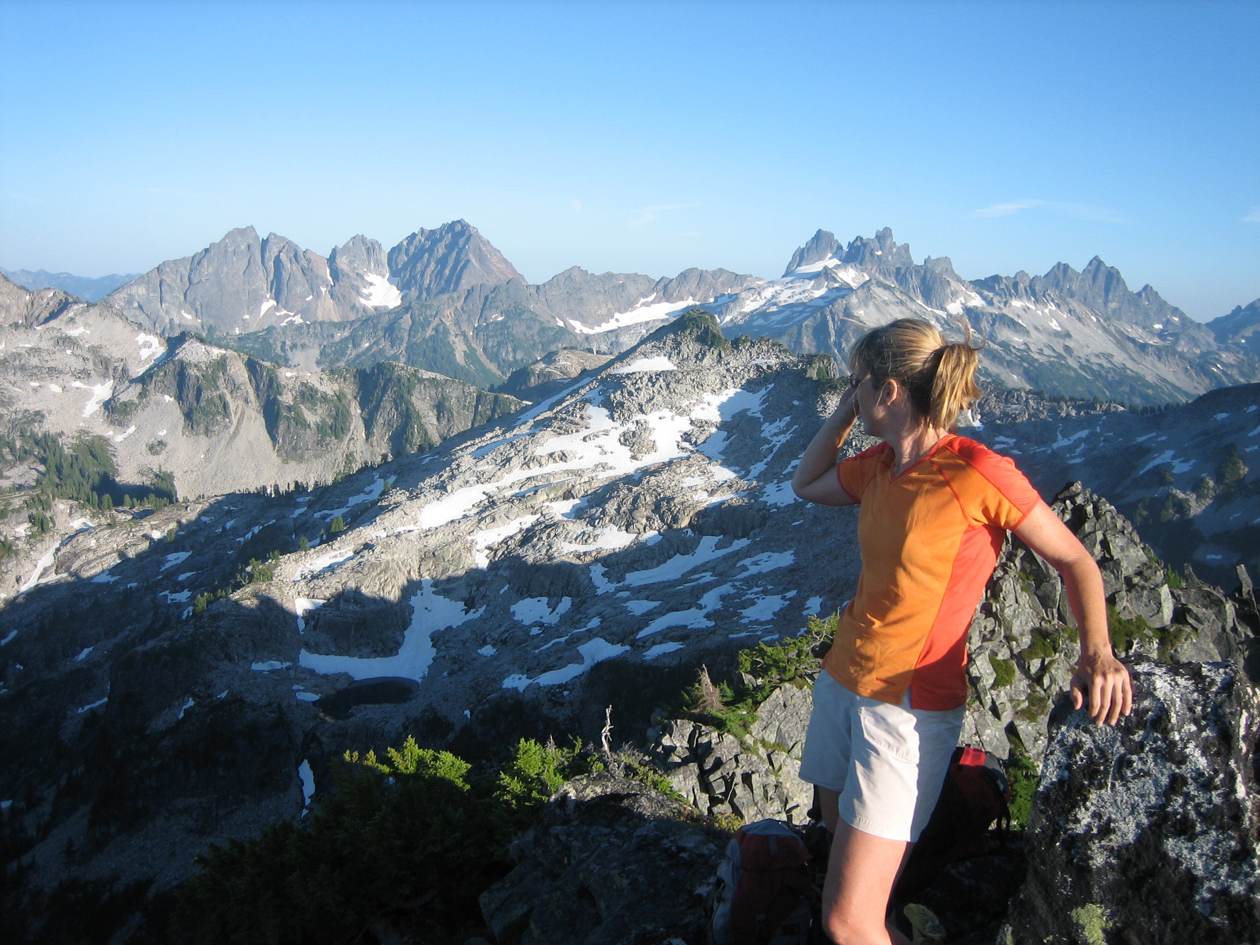 hiker on the summit of Camp Robber Peak with the Snoqualmie Mountains in the background
