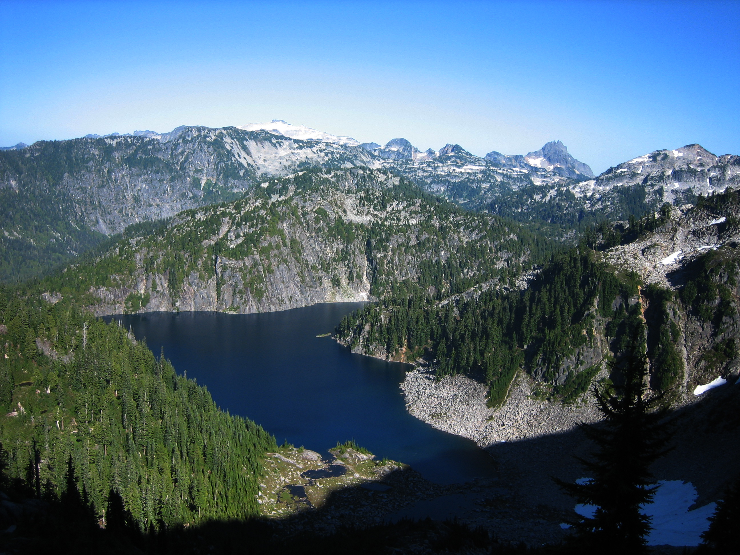 Mt Hinman and Bears Breast Mountain Above Big Heart Lake with rock slab cliffs and evergreen trees