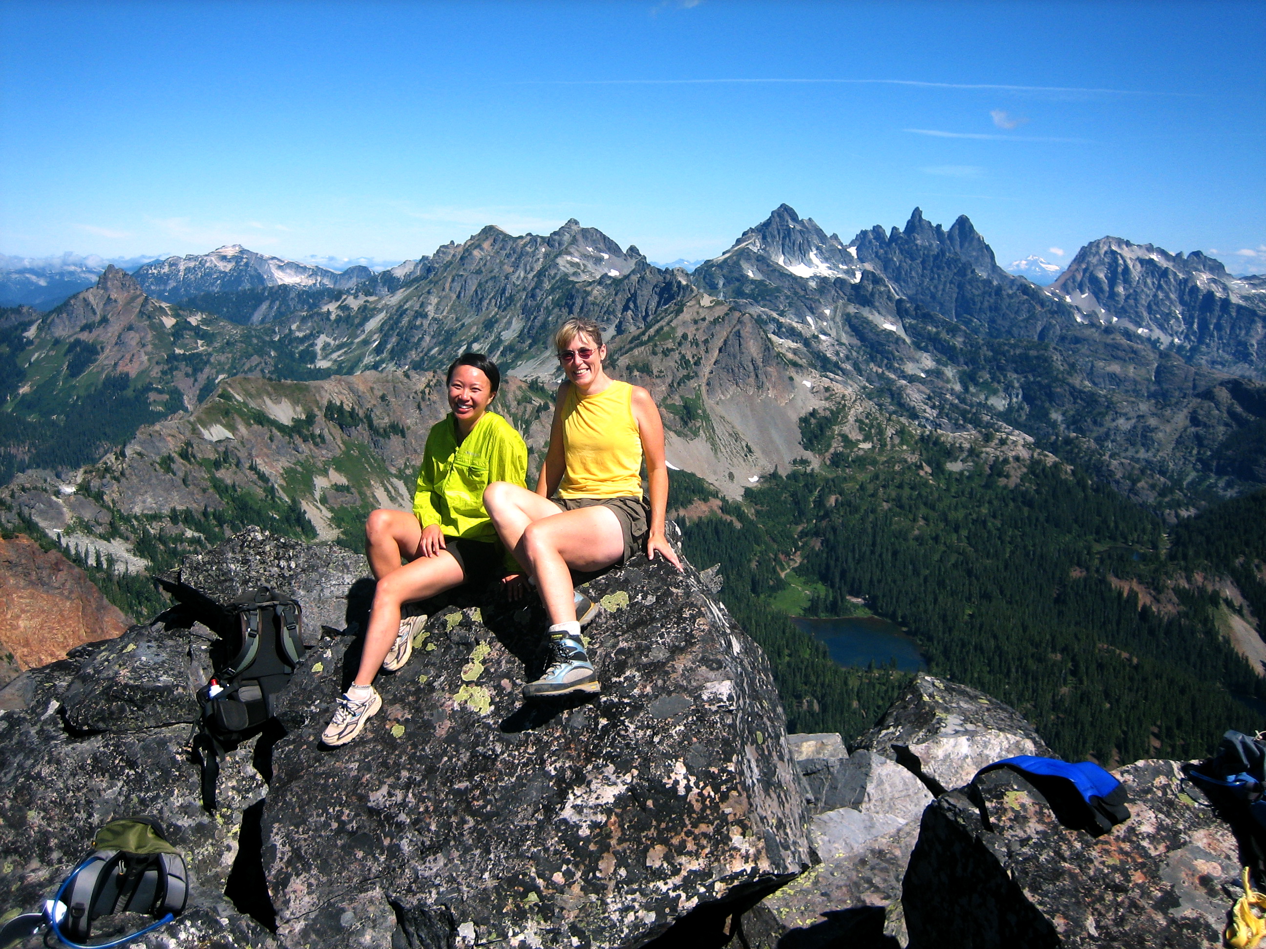 mountain climbers taking a break on the summit rock of Hibox Peak with the Snoqualmie Mountains in the background